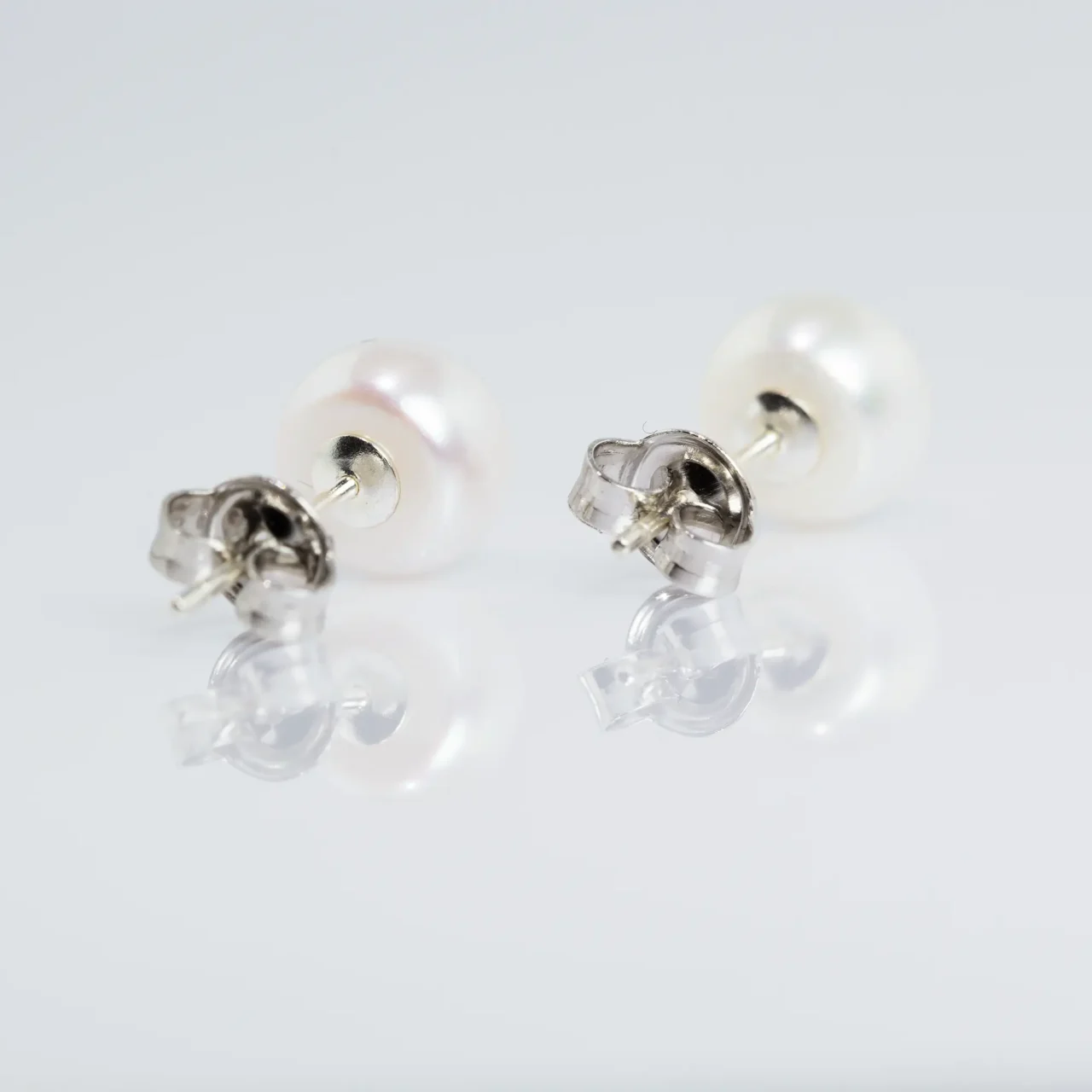Elegant white pearl stud earrings on a soft white background