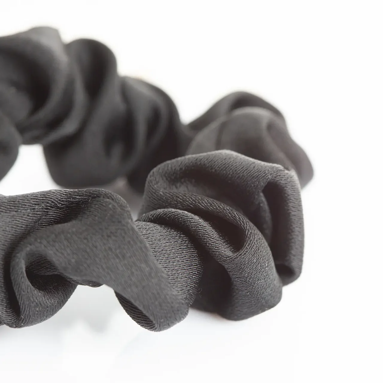 Elegant black fabric scrunchie with a white flower charm and gold accent