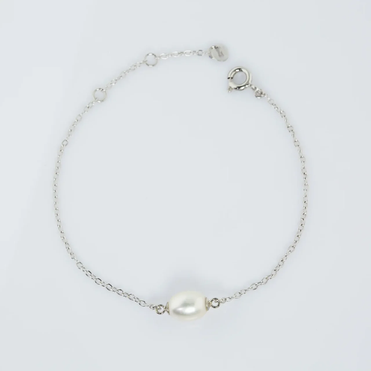 Delicate silver chain bracelet with a single white pearl centerpiece.