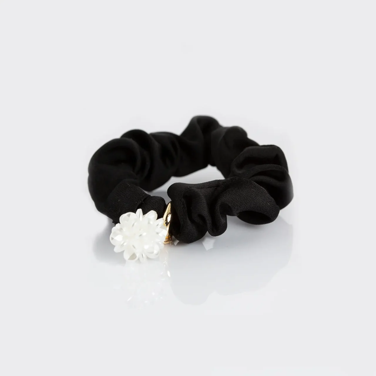 Elegant black fabric scrunchie with a white flower charm and gold accent