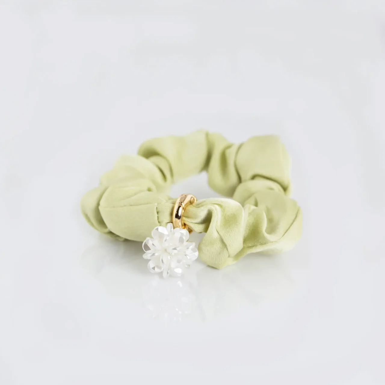 Elegant green fabric scrunchie with a white flower charm and gold accent