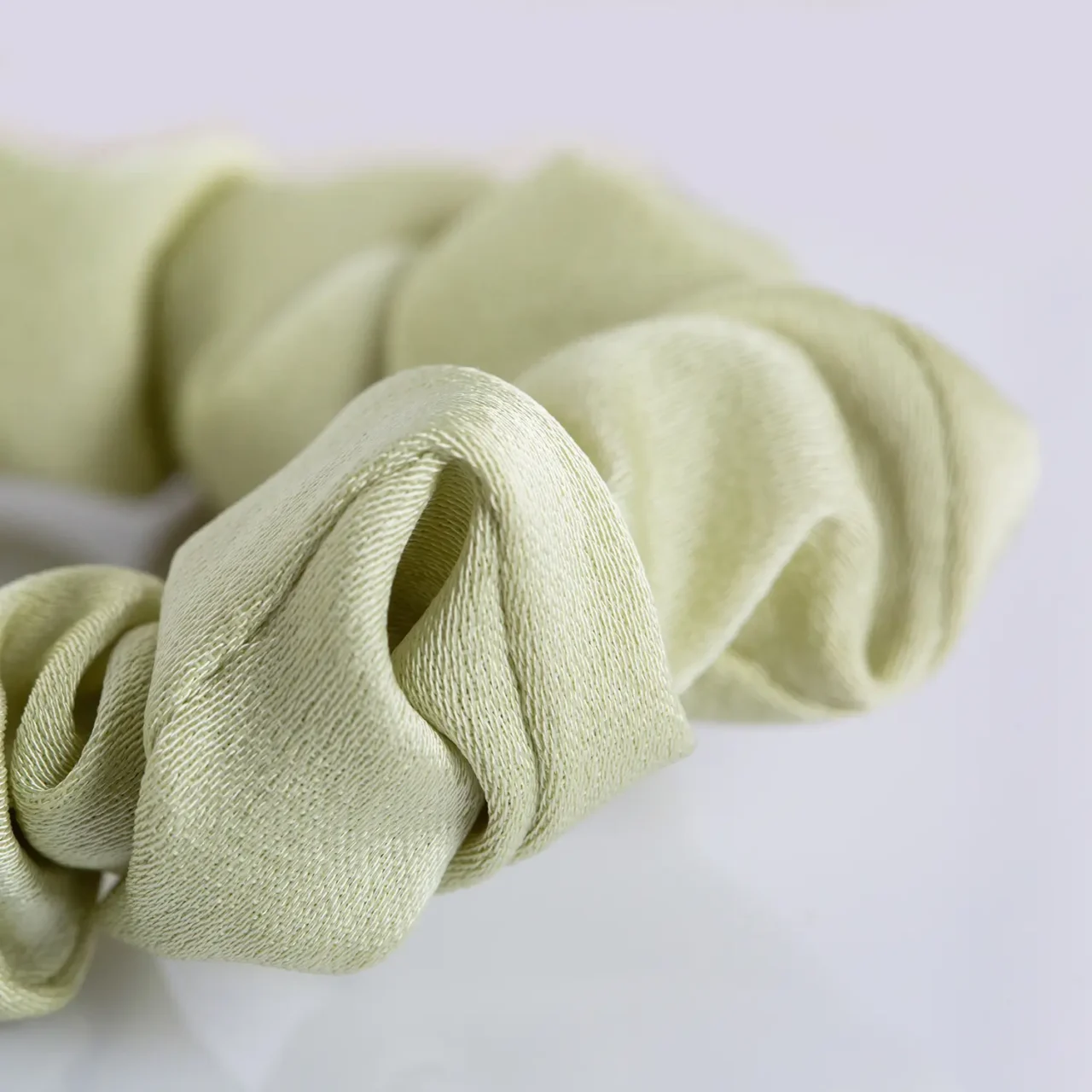 Elegant green fabric scrunchie with a white flower charm and gold accent