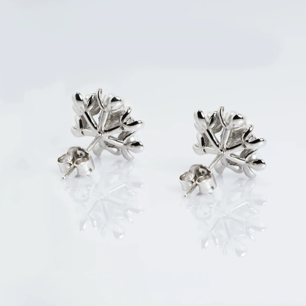 Intricate pearl and silver floral stud earrings with zirconia stones accents